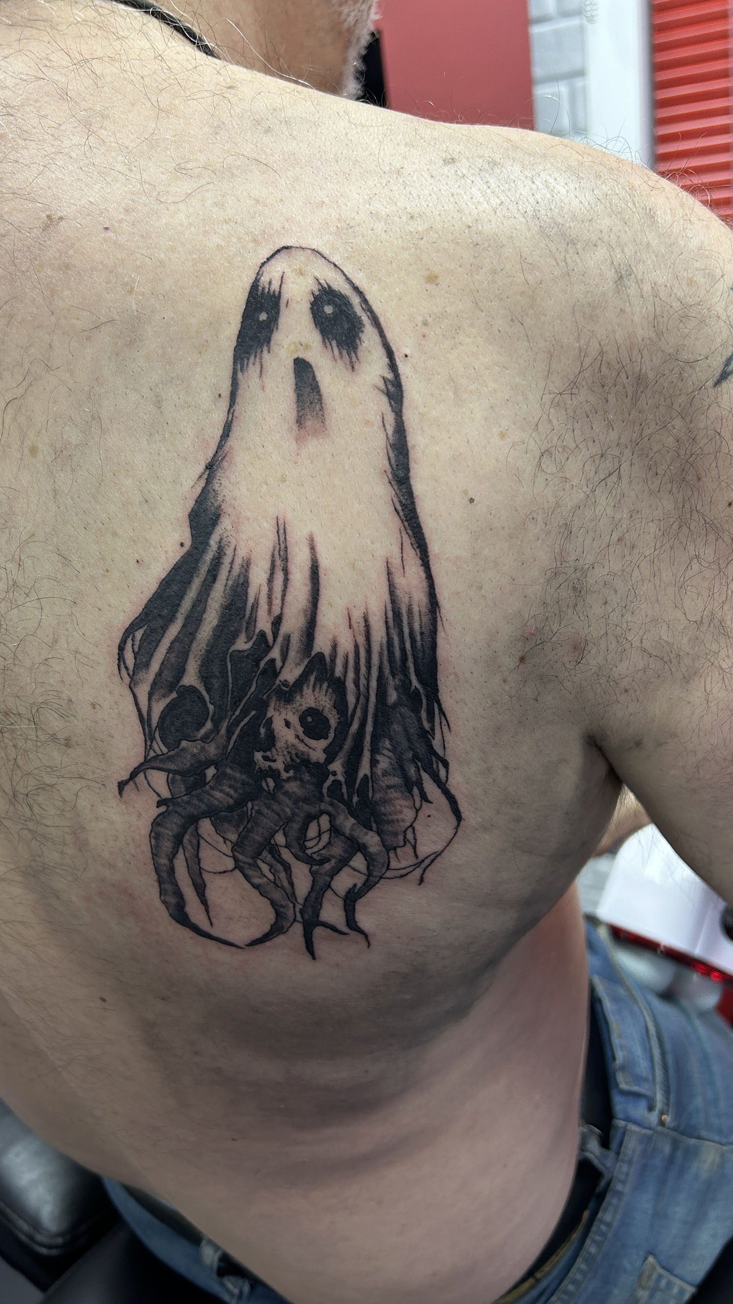 Ghost tattoo on back shoulder blade